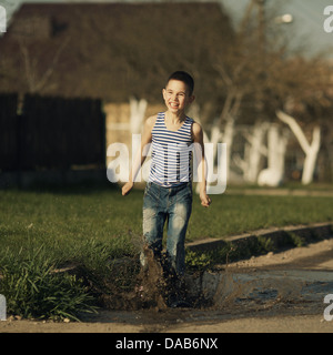 Peu d'happy boy standing in puddle Banque D'Images