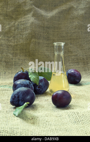 Avec eau de vie de prune frais et savoureux fruits sur une nappe. Banque D'Images