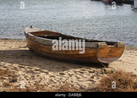 Vieux bateau à rames en bois tiré hors de l'eau Et s'asseoir sur la plage de sable à Baiter Poole Banque D'Images