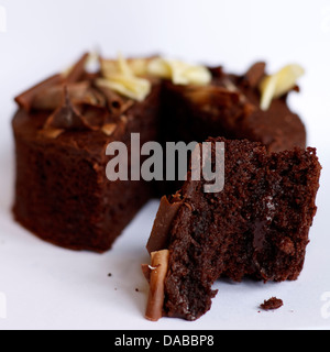 Un gâteau au chocolat mangé en partie sur un fond blanc Banque D'Images
