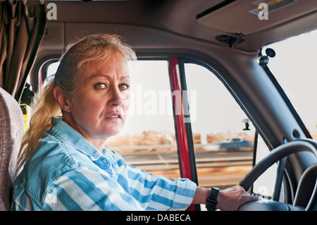 Femme blonde en conversation sur le téléphone cellulaire en conduisant un gros camion. Banque D'Images