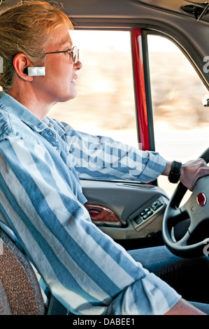 Femme blonde en conversation sur le téléphone cellulaire en conduisant un gros camion. Banque D'Images