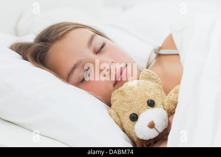 Cheerful girl dormir avec son ours en peluche Banque D'Images