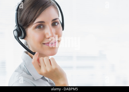 Pretty call centre agent smiling at the camera Banque D'Images