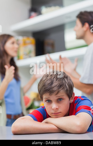 Triste petit garçon à l'écoute de ses parents se disputer Banque D'Images