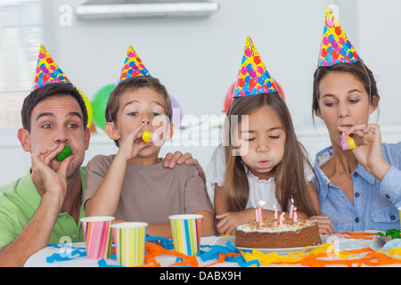 Famille avec party horn celebrating their daughter party Banque D'Images