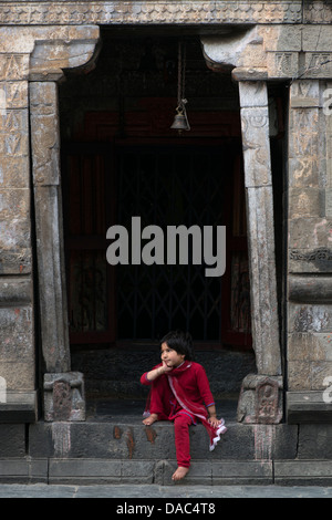 Un enfant est assis à l'entrée endommagées par le tremblement de terre d'un temple hindou Narsing à Bharmour, Himachal Pradesh, Inde Banque D'Images