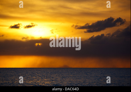 Coucher du soleil doré après une éruption du volcan de Montserrat vu de Antigua, l'île de Redonda sur l'horizon. Banque D'Images