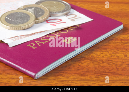 Passeport britannique avec des pièces et des billets en euros sur table en bois Banque D'Images