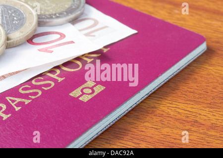 Passeport britannique avec des pièces et des billets en euros sur table en bois Banque D'Images