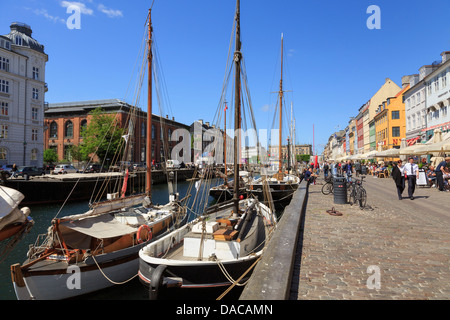 Vieux bateaux amarrés sur canal par la rue piétonne waterfront avec les cafés en plein air à Nyhavn, Copenhague, Danemark, Nouvelle-Zélande Banque D'Images