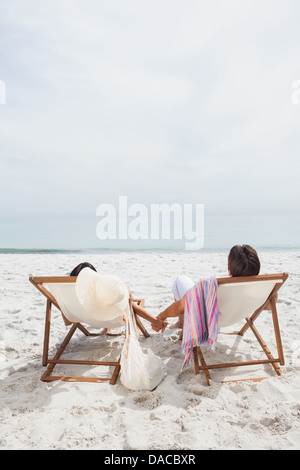 Couple à la mer sur leurs chaises longues Banque D'Images