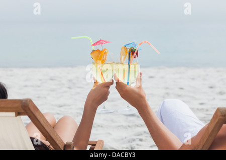 Couple clinking glasses of cocktail on beach Banque D'Images