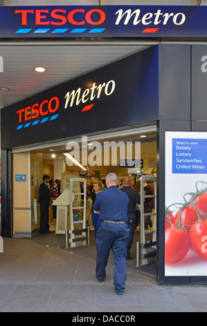 Les gens qui marchent à l'entrée d'achats ci-dessous signe à City de Londres Métro supermarché Tesco business store d'épicerie au détail dans les grands bureaux, England UK Banque D'Images