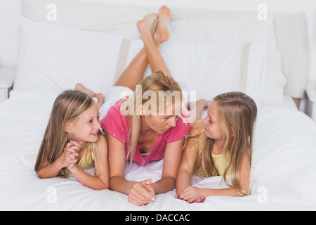 Des jumeaux se détendre avec leur mère au lit Banque D'Images