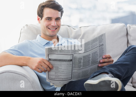 L'homme lire un journal assis sur un canapé Banque D'Images