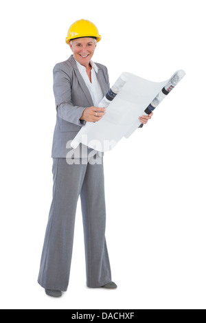 Smiling architect wearing hardhat et plan holding Banque D'Images