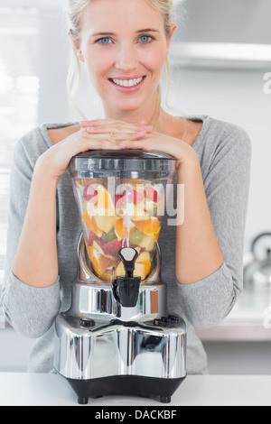 Femme blonde appuyée sur son presse-agrumes Banque D'Images