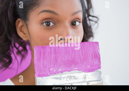 Pretty woman holding paintbrush avec peinture sur son nez Banque D'Images