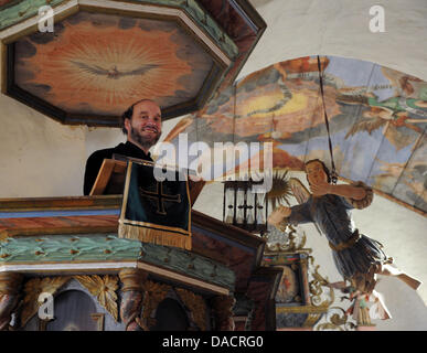 Ministre Joachim Boeckels se trouve à côté de la statue en bois d'un ange s'élève à l'intérieur du baptême 13e siècle église dans Niebendorf, Allemagne, 06 décembre 2011. L'église luthérienne est propriétaire d'une collection de statues baroques en bois du xviiie siècle. L'ange s'élance sous le toit après avoir été caché dans le grenier sous un tas de débris. Photo : Bernd Settnik Banque D'Images