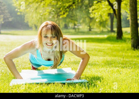 Instructeur de conditionnement physique des femmes faisant de l'exercice en parc d'été vert pushups Banque D'Images