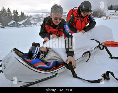 Les membres d'un service de secours en montagne de la Croix-Rouge allemande (DRK) sont illustrés au cours d'un exercice de sauvetage à une pente de ski à Oberwiesenthal, Allemagne, le 19 décembre 2011. Le service de sauvetage en montagne fait face à quelque 550 opérations de sauvetage par saison. Les skieurs et planchistes surtout besoin de l'aide du service. Photo : Hendrik Schmidt Banque D'Images