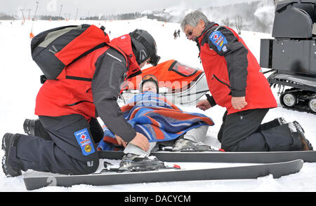 Les membres d'un service de secours en montagne de la Croix-Rouge allemande (DRK) sont illustrés au cours d'un exercice de sauvetage à une pente de ski à Oberwiesenthal, Allemagne, le 19 décembre 2011. Le service de sauvetage en montagne fait face à quelque 550 opérations de sauvetage par saison. Les skieurs et planchistes surtout besoin de l'aide du service. Photo : Hendrik Schmidt Banque D'Images