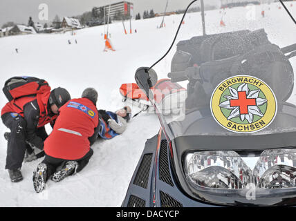 Les membres d'un service de secours en montagne de la Croix-Rouge allemande (DRK) sont illustrés au cours d'un exercice de sauvetage à une pente de ski à Oberwiesenthal, Allemagne, le 19 décembre 2011. Le service de sauvetage en montagne fait face à quelque 550 opérations de sauvetage par saison. Les skieurs et planchistes surtout besoin de l'aide du service. Photo : Hendrik Schmidt Banque D'Images