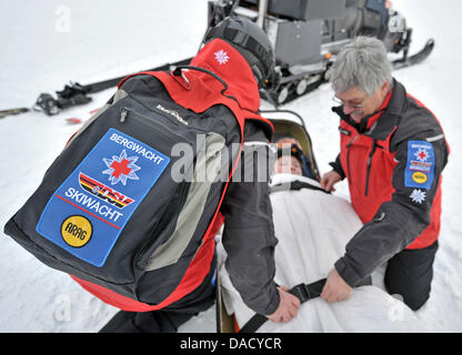 Les membres d'un service de secours en montagne de la Croix-Rouge allemande (DRK) sont illustrés au cours d'un exercice de sauvetage à une pente de ski à Oberwiesenthal, Allemagne, le 19 décembre 2011. Le service de sauvetage en montagne fait face à quelque 550 opérations de sauvetage par saison. Les skieurs et planchistes surtout besoin de l'aide du service. Photo : Hendrik Schmidt Banque D'Images