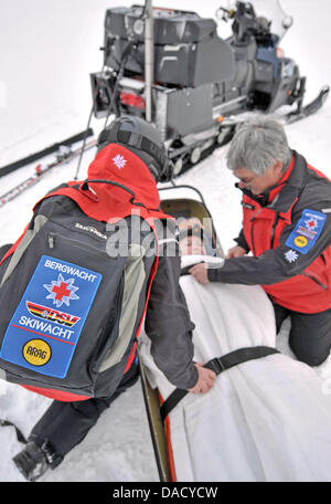 Les membres d'un service de secours en montagne de la Croix-Rouge allemande (DRK) sont illustrés au cours d'un exercice de sauvetage à une pente de ski à Oberwiesenthal, Allemagne, le 19 décembre 2011. Le service de sauvetage en montagne fait face à quelque 550 opérations de sauvetage par saison. Les skieurs et planchistes surtout besoin de l'aide du service. Photo : Hendrik Schmidt Banque D'Images