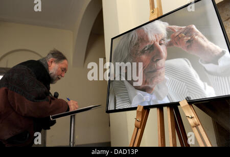 Un homme signe son nom dans un livre de condoléances à côté d'un portrait de Johannes Heesters avant les funérailles de Johannes Heesters au cimetière du nord à Munich, Allemagne, le 30 décembre 2011. Parents, collègues et amis sayed adieu à l'acteur et chanteur, décédé la veille de Noël 2011 à l'âge de 108. Photo : Tobias Hase Banque D'Images