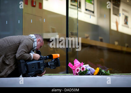 Une caméra film homme une bougie allumée devant l'Apple Store en direction de Frankfurt, Allemagne, 6 octobre 2011. Steve Jobs, co-fondateur et directeur de longue date d'Apple, est décédé ce mercredi 5 octobre 2011, le cancer de l'âge de 56 ans en Californie. Emploi avait lutté contre le cancer du pancréas pendant de nombreuses années. Photo : Frank Rumpenhorst Banque D'Images