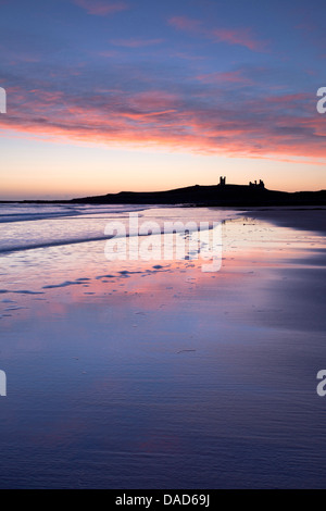 À travers la baie Embleton au lever du soleil vers les ruines du château de Dunstanburgh, Embleton, près de Alnwick, Northumberland, England, UK Banque D'Images