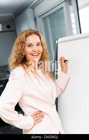 Smiling businesswoman écrit sur le tableau in office Banque D'Images