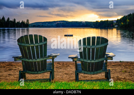 Deux chaises en bois sur la plage du lac de détente au coucher du soleil. Le parc provincial Algonquin, au Canada. Banque D'Images