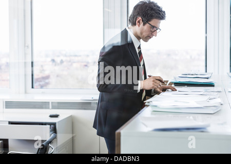 Businessman standing in office looking at paperwork