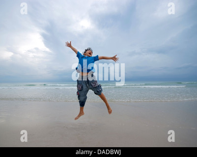 Heureux garçon sautant sur la plage le matin à Koh Samui, Thaïlande.