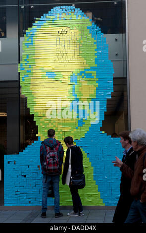 Les passants se tenir devant un portrait géant de la mort du fondateur d'Apple Steve Jobs a fait de milliers de Post-it-notes à une fenêtre d'un Apple-Store à Munich, Allemagne, 18 octobre 2011. Avis importants peut être écrit sur les notes. L'emploi est mort le 05 octobre 2011 à l'âge de 56 ans. Photo : PETER KNEFFEL Banque D'Images