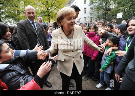 La chancelière allemande, Angela Merkel, est accueilli par les élèves d'Erika Mann École primaire dans le quartier de Wedding à Berlin, Allemagne, 20 octobre 2011. Merkel veut se faire une idée de la situation à une école avec de nombreux non-langue maternelle allemande. Photo : RAINER JENSEN Banque D'Images