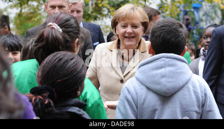 La chancelière allemande, Angela Merkel, est accueilli par les élèves d'Erika Mann École primaire dans le quartier de Wedding à Berlin, Allemagne, 20 octobre 2011. Merkel veut se faire une idée de la situation à une école avec de nombreux non-langue maternelle allemande. Photo : RAINER JENSEN Banque D'Images