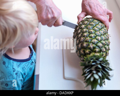 Boy watching woman slicing pineapple Banque D'Images