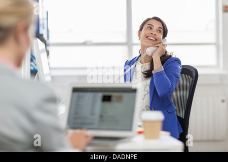 Mid adult woman using telephone in office Banque D'Images