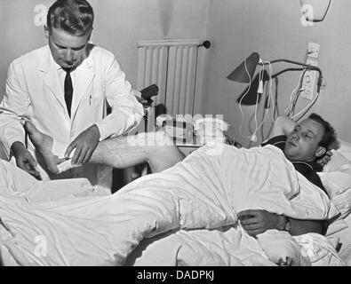 (Afp) - Un fichier photo datée du 30 novembre 1961 illustre joueur de football allemand Uwe Virginia Afflerbach (R) d'être traités sur une jambe cassée à Hambourg, Allemagne. Le 05 novembre 2011, l'Uwe a 75 ans Virginia Afflerbach. Photo : Hans Heckmann Banque D'Images