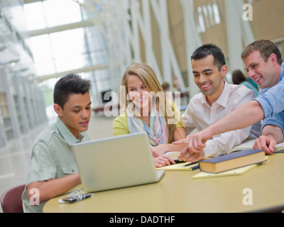 Jeune homme et d'étudier avec les tuteurs pointing at laptop Banque D'Images