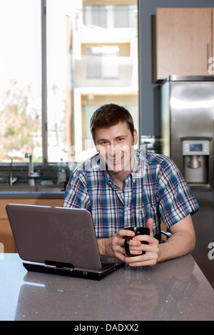 Mid adult man using laptop in office portrait Banque D'Images