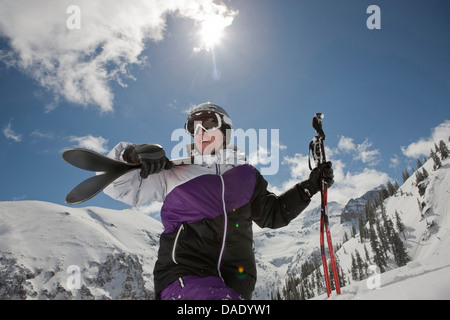 Mid adult man in skiwear transportant des skis sur l'épaule, smiling Banque D'Images