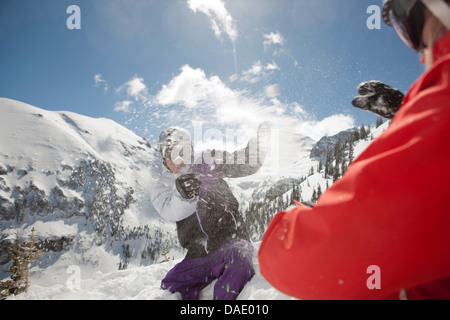 Mid adult man and young woman in skiwear having snowball fight Banque D'Images