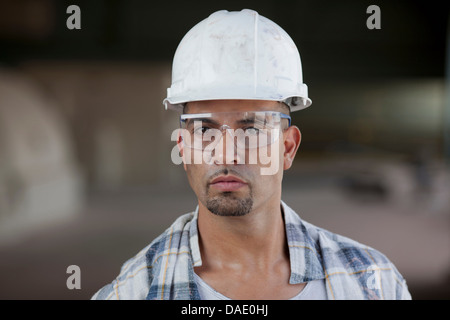 Young construction worker wearing hard hat, portrait Banque D'Images
