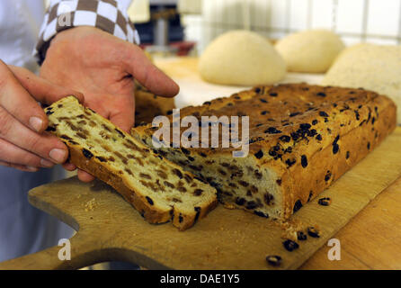 Un des petits Klaben est coupé en tranches au 'Schnaare' bakery à Brême, Allemagne, 03 novembre 2011. Un Klaben est type de Stollen, une sorte de pain à base de fruits secs, d'orange et le zeste de citron, un rhum et autres droits fondamenteux almods ingrédients. L'Klaben est étroitement associée à la ville hanséatique de Brême et surtout le commerce avec les marchandises coloniales qui ont fourni les ingrédients de haute qualité. Ol Banque D'Images