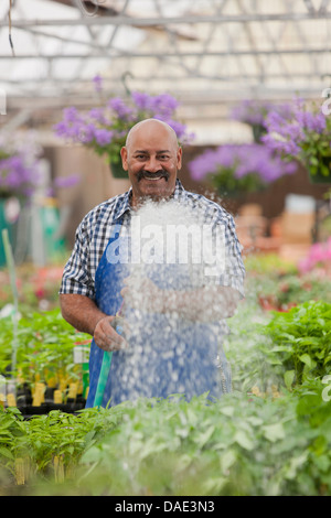 Jardinier l'arrosage des plantes matures en centre-jardin, portrait Banque D'Images